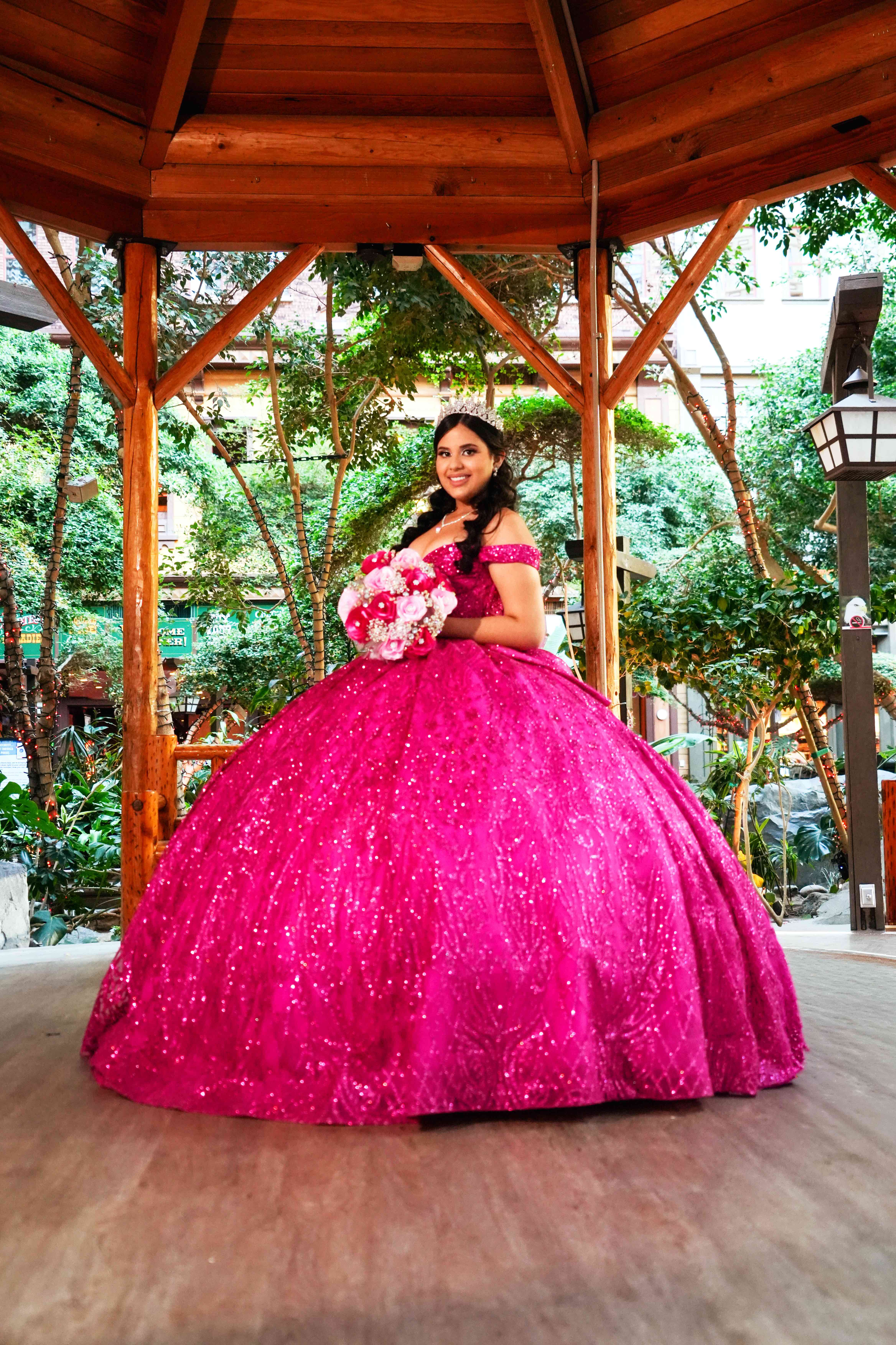 Quinceañera in a pink gown at a garden gazebo