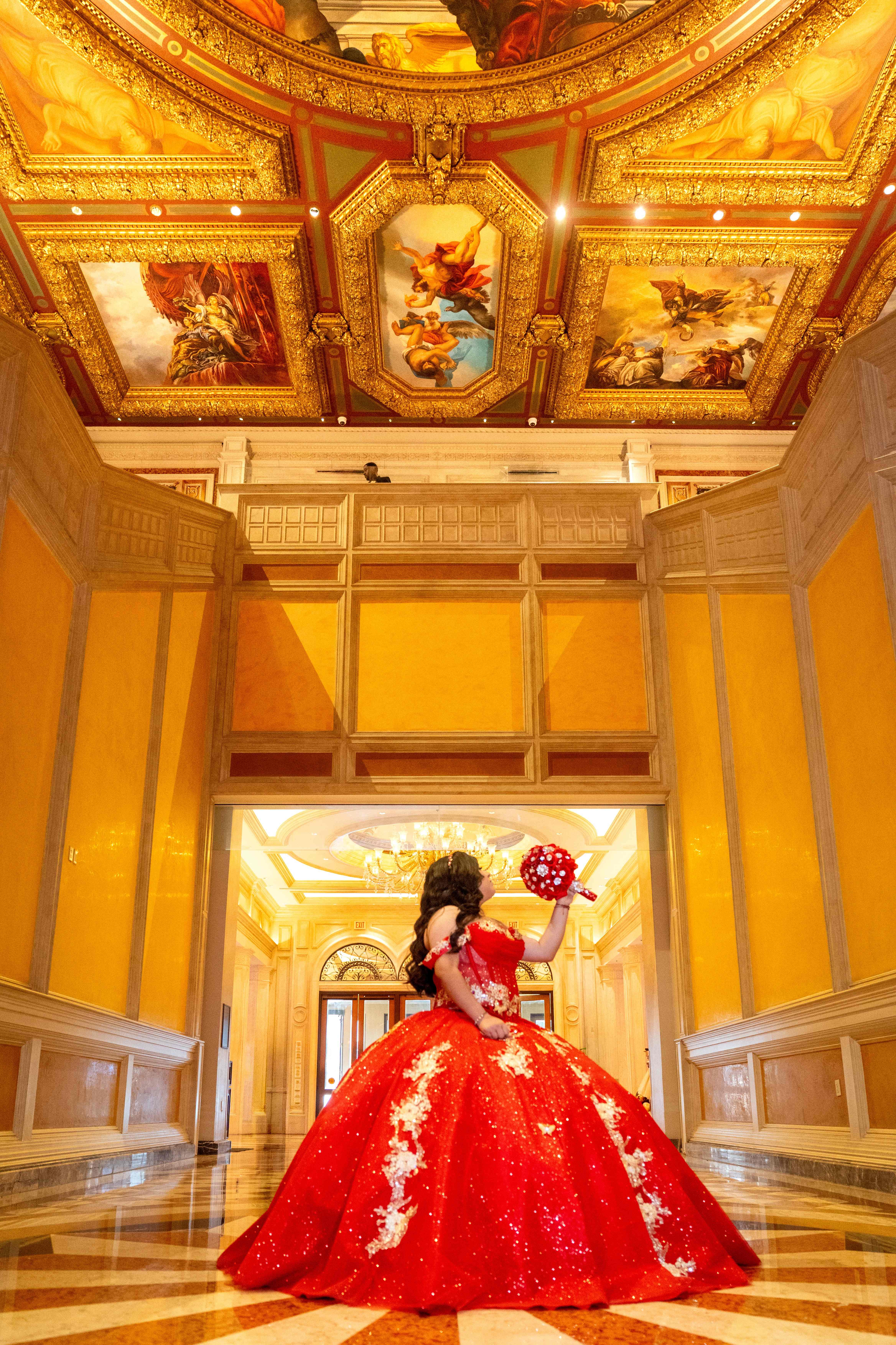 Quinceañera in red gown in an ornate gold hall